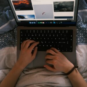 a person typing on a laptop on a bed