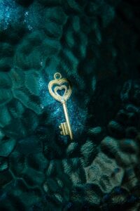 A golden heart-shaped key resting on a teal textured surface, offering a unique contrast.