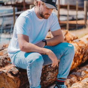 man in blue t-shirt and blue denim jeans sitting on brown wood log during daytime