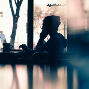 silhouette of a person sitting in front of a laptop