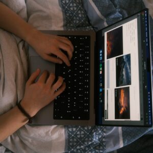 a person using a laptop computer on a bed