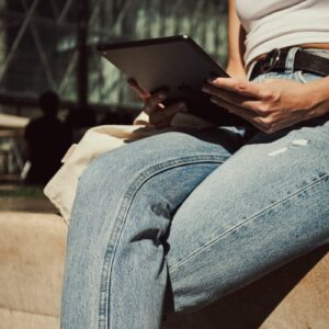 a woman sitting on a wall using a tablet