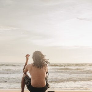 a man sitting on top of a surfboard on a beach